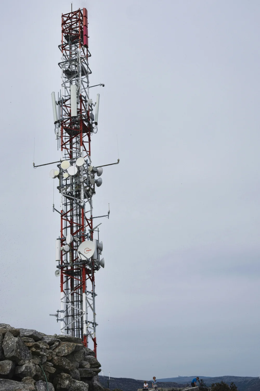 A red and white antenna tower reaching into an open sky